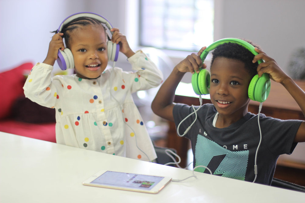 Two kids with headphones, smiling and looking at camera